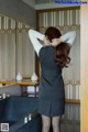 A woman standing in front of a bathtub with her back to the camera.