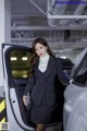 A woman in a business suit standing next to a car.