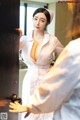 A woman in a white nurse outfit is looking at herself in the mirror.