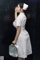 A woman in a white nurse outfit holding a white bag.