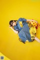 A woman laying on a yellow surface with a yellow pillow.