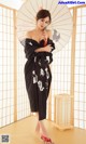 A woman in a black kimono holding an umbrella.