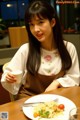 A woman sitting at a table with a plate of food.