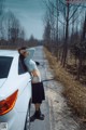 A woman leaning on the hood of a white car.