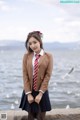 A woman in a school uniform standing by the water.