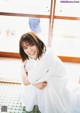 A woman in a white dress sitting on a tiled floor.