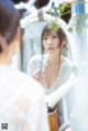 A woman in a white dress looking at herself in a mirror.