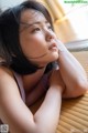 A woman laying on a bed with her hand on her chin.