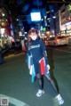 A woman standing in the middle of a city street at night.