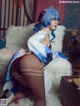 A woman with blue hair is sitting on a white fur rug.