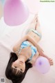 A young girl laying on the floor with balloons.