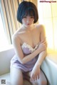 A woman in a purple lingerie sitting on a white couch.