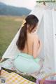 A woman sitting on a blanket in front of a teepee.