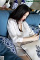 A woman sitting on a blue couch looking at her phone.