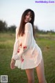 A woman in a white dress standing in a field.