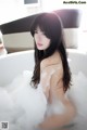 A woman sitting in a bathtub filled with foam.