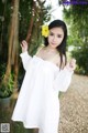 A woman in a white dress holding a yellow flower.