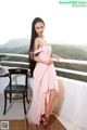 A woman in a pink dress standing on a balcony.