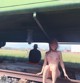 A naked woman sitting on a train track next to a man.