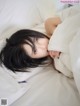 A woman laying in bed with her head under a pillow.