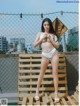 A woman in a white bikini standing on a wooden bench.