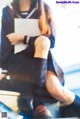 A woman in a school uniform sitting on an escalator.