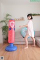 A woman in a pink dress standing next to an inflatable punching bag.