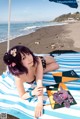 A woman laying on a beach next to an umbrella.